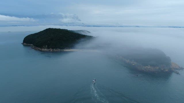 Boat sailing near a foggy island