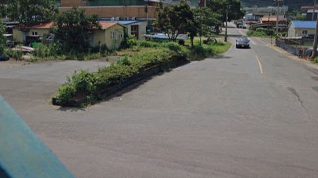 Car driving past rural buildings on a sunny day