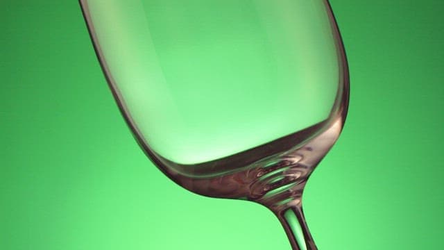 Pouring carbonated drinks into wine glass on green background