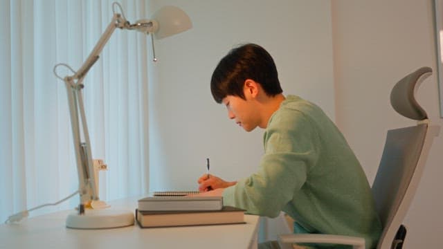Man writing at a desk in a calmly lit room