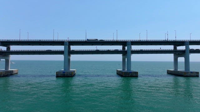 Vehicles crossing a Gwangan Bridge over the calm sea on a clear day