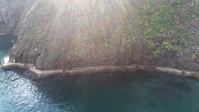 Waves Sparkling in the Sunlight and a Rocky Cliff Walkway
