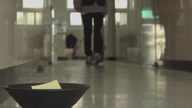 Person walking down the hallway and picking up a note from a bowl