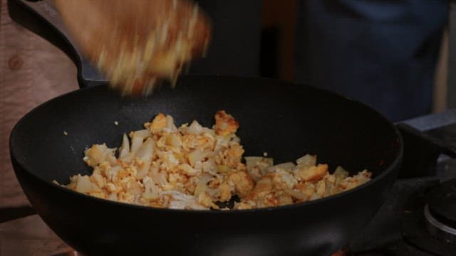 Cooking fried rice in a wok with wooden spatula