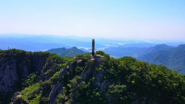 Mountain landscape with a tower commemorating the summit under a clear sky