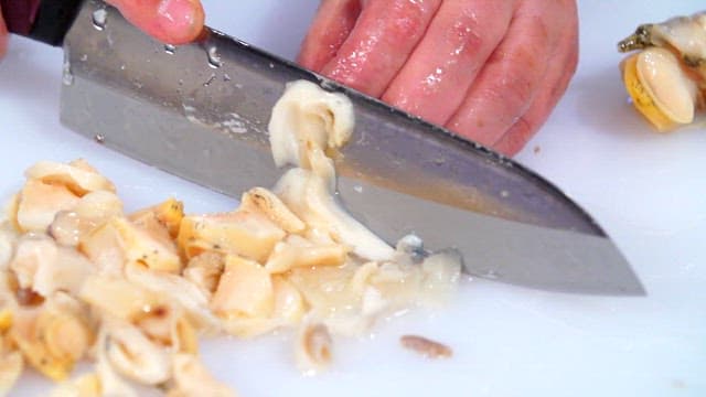 Slicing fresh sea snails on a cutting board