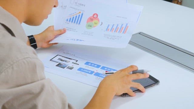 Person Analyzing Financial Charts Written on Paper