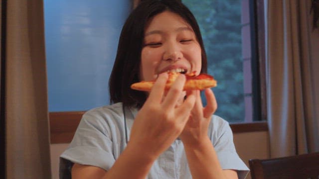 Woman enjoying a slice of pizza indoors