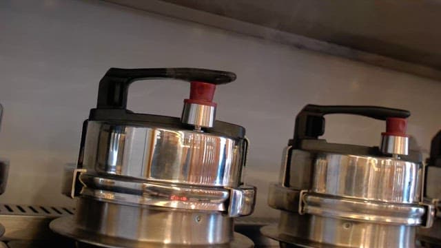 Pressure cookers releasing steam in a kitchen