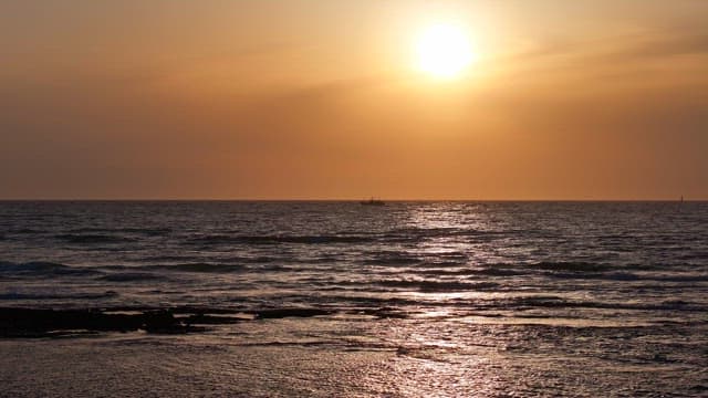 Sunset over a calm ocean with gentle waves