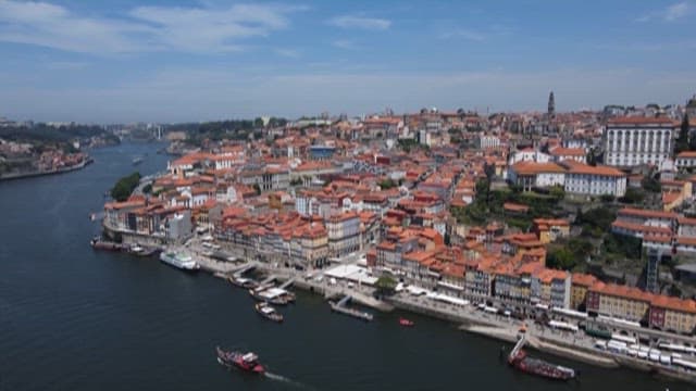 Riverside City with Red-roofed Buildings and Boats on a Sunny Day