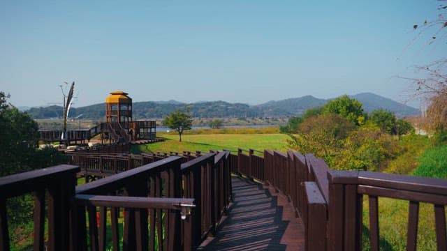 Wooden walkway in a scenic park with an observation tower on a clear day