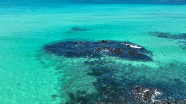 Clear turquoise sea with dark rocks