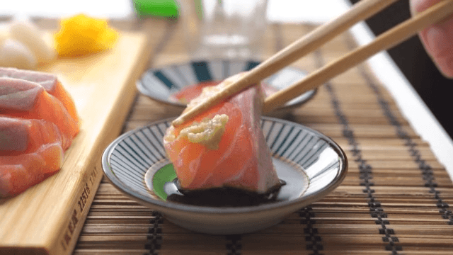 Side view of salmon sashimi, topped with wasabi and dipped in soy sauce, after drinking alcohol
