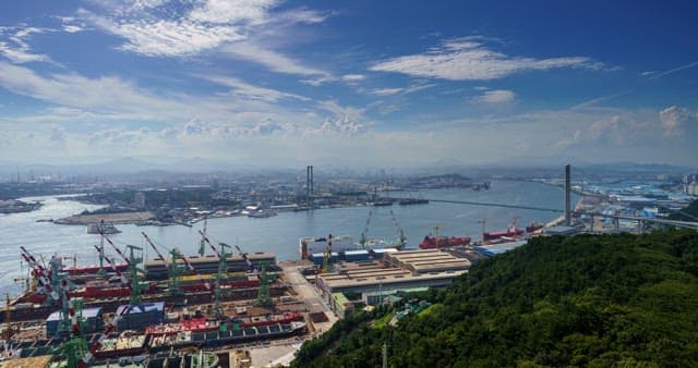 View of a shipyard in Ulsan with cranes and ships from day to night