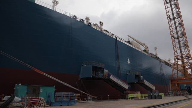 Huge cargo ship docked at a shipyard under a cloudy sky