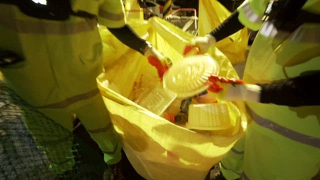 Street cleaners sorting plastic waste in large yellow bags