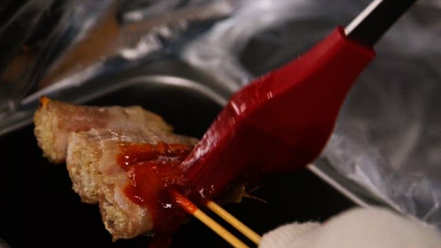 Brushing sauce to grilled skewers in the kitchen