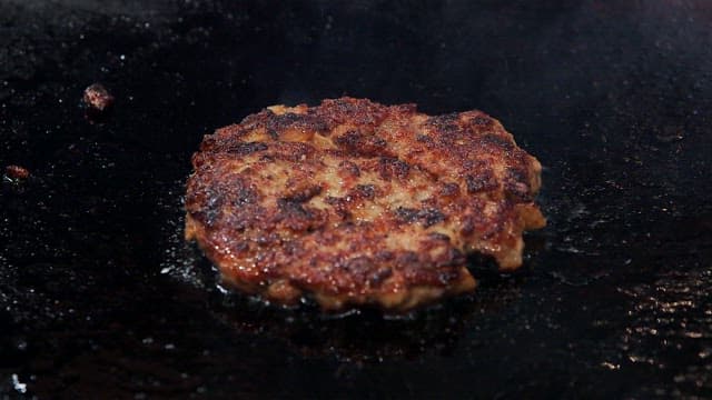 Juicy burger patty sizzling on a grill