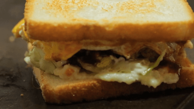 Sandwich with egg and sauce being prepared