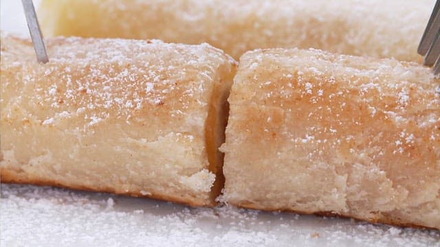 Close-up of sugar-dusted pastry rolls on a white plate