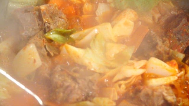 The process of cooking food with vegetables and meat in red soup