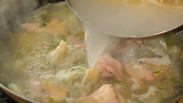 Noodles and dumplings in boiling chicken soup