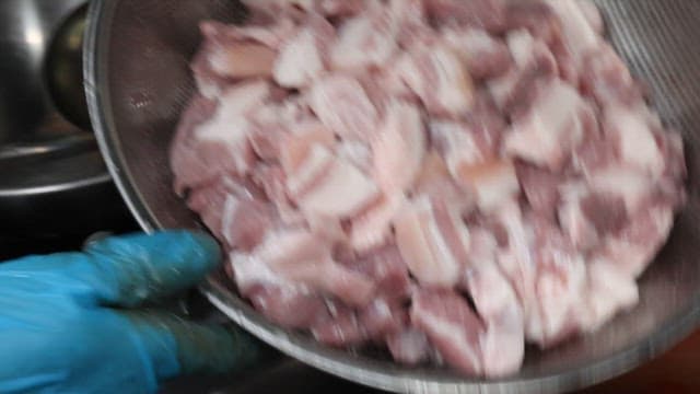 Adding fresh pork to kimchi stew in a restaurant kitchen