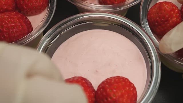Careful placement of strawberries on a pink mousse dessert.