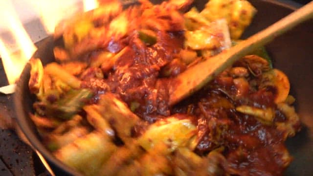 Stir-fried octopus with spicy sauce prepared in a restaurant kitchen