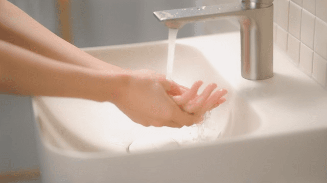 Person washing hands at a sink in a clean bathroom