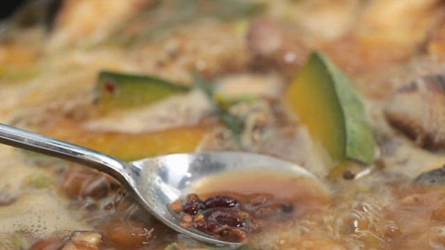 Spoonful of boiling Cheonggukjang with a variety of vegetables and tofu