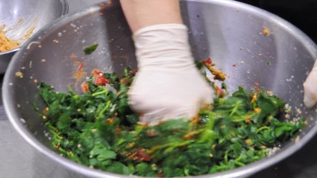 Seasoned Spinach Made by Mixing Seasoning in a Metal Bowl