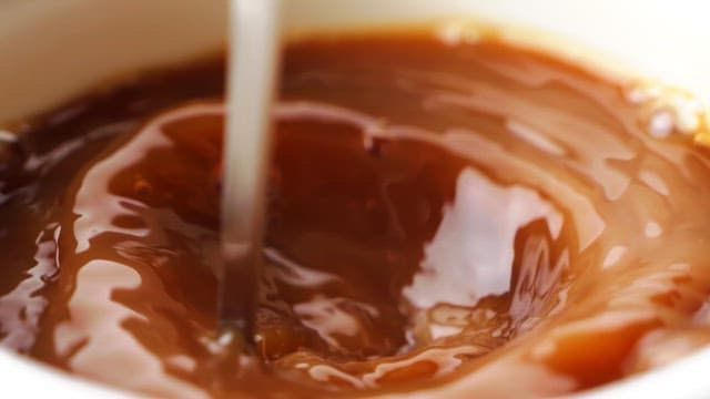 Stirring coffee in a white cup with a spoon
