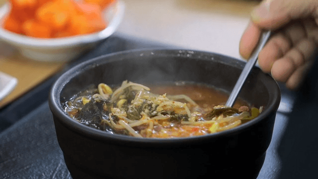 Mixing hot and spicy Korean beef soup with spoon