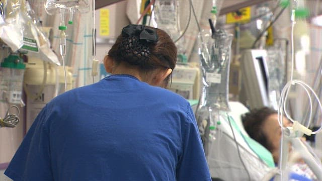 Nurse tending to a patient in a busy ICU