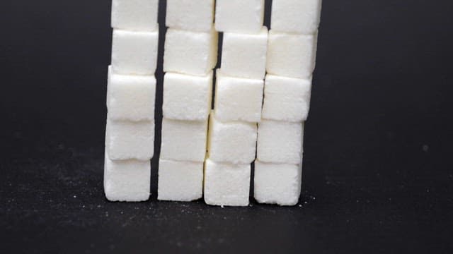 Stacked white sugar cubes on a black surface
