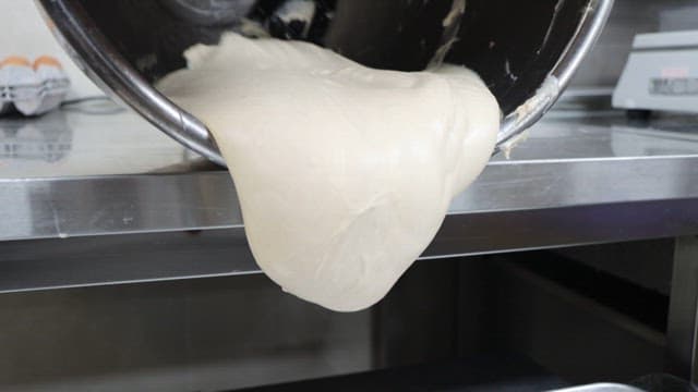 Dough pouring from a bowl onto a metal tray