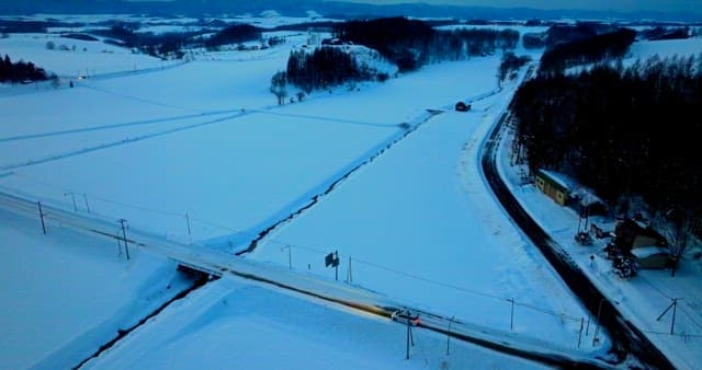 Twilight over snowy countryside with passing car