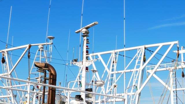 Radar tower and antennas on a ship under a clear blue sky