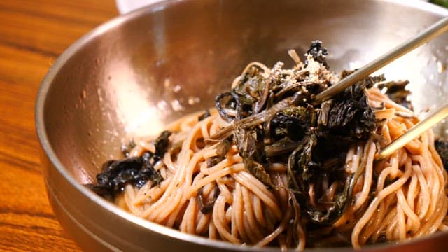 Mixing perilla oil makguksu with chopsticks