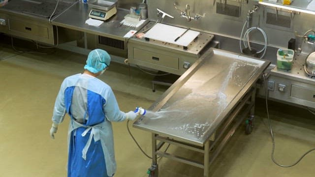 Person cleaning the autopsy table in the morgue