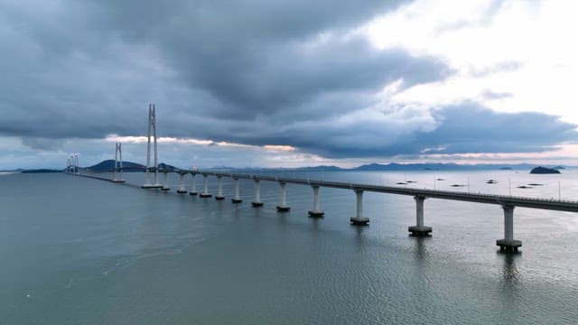 Long bridge over a calm sea under cloudy skies