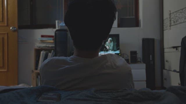 Person in a dimly lit room watching a movie on television