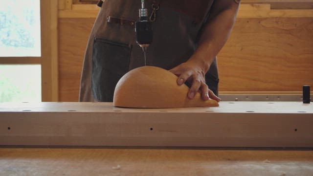 Person drilling a gourd on a workbench