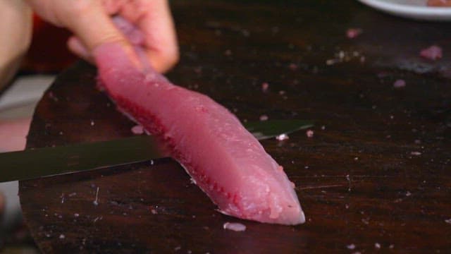 Slicing fresh tuna on a wooden board