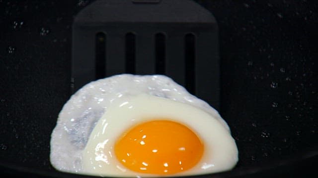 Fried egg being cooked and placed on a plate