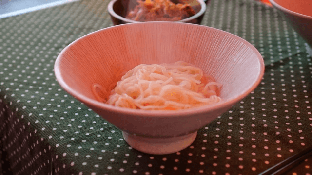 Placing steaming noodles into a bowl