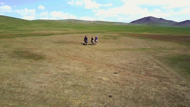 People riding horses on a vast plain