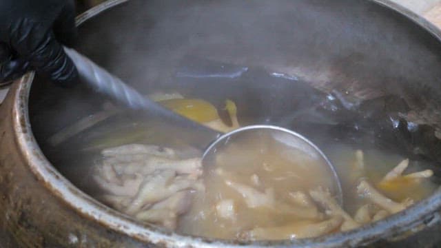 Boiled chicken feet scooped up with a ladle